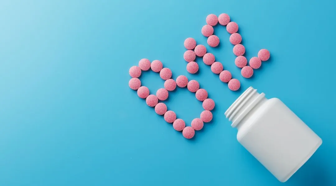 Pink vitamin B12 tablets spelling “B12” and forming a heart shape next to white bottle